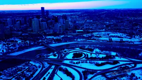 Invierno-En-El-Centro-De-La-Ciudad-De-Edmonton-Puesta-De-Sol-Vuelo-Inverso-Pan-Fuera-Del-Lado-Este-Del-Centro-Sobre-El-Borde-De-Los-Ríos-Clásico-Icónico-Bajo-Nivel-Y-Puentes-James-Macdonald-Con-La-Comunidad-De-Riverdale-Cubierta-De-Nieve-1-2