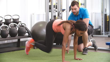 young woman working out in gym under supervision of trainer