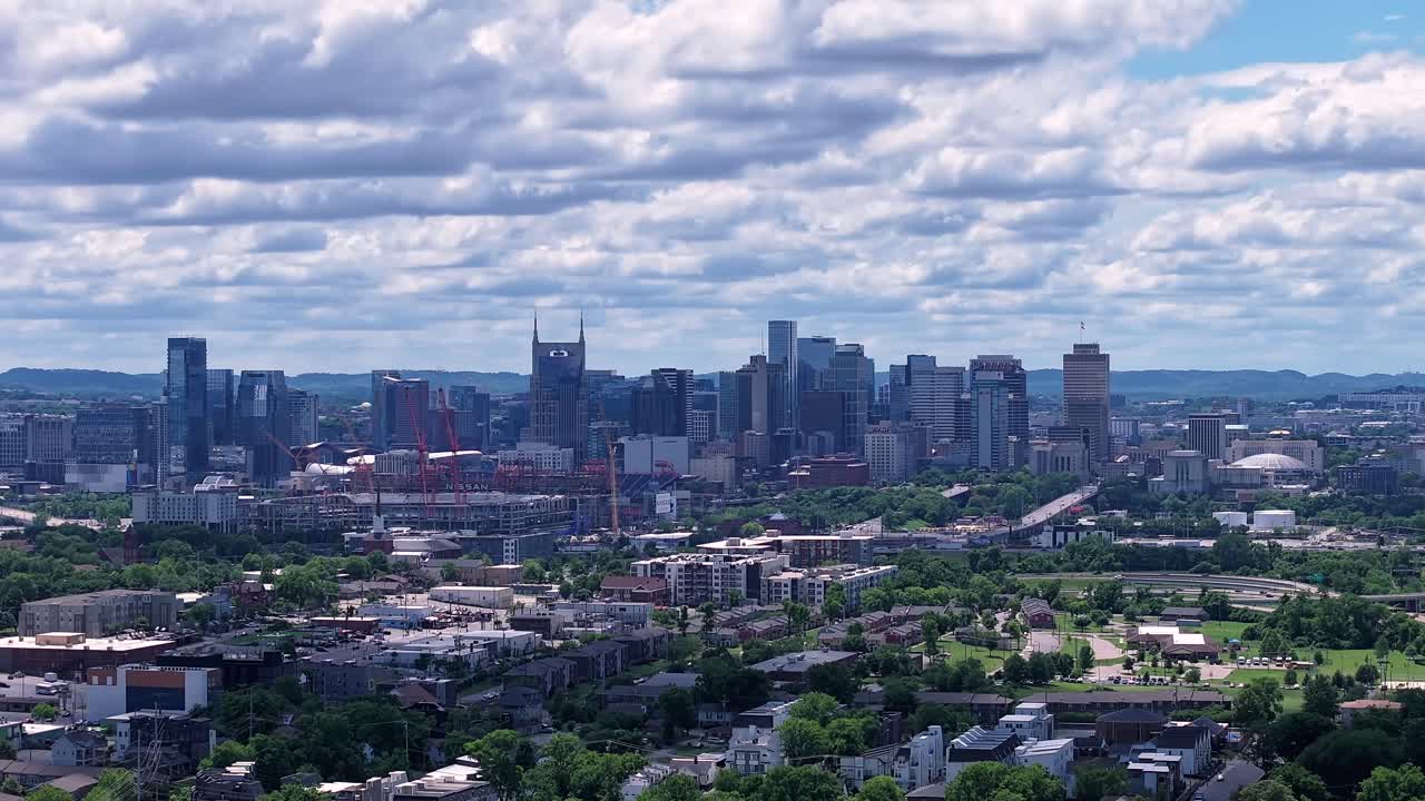 Nashville, Tennessee skyline under a flowing cloudscape that casts shadows across the city's bustling landscape - forward aerial hyper lapse