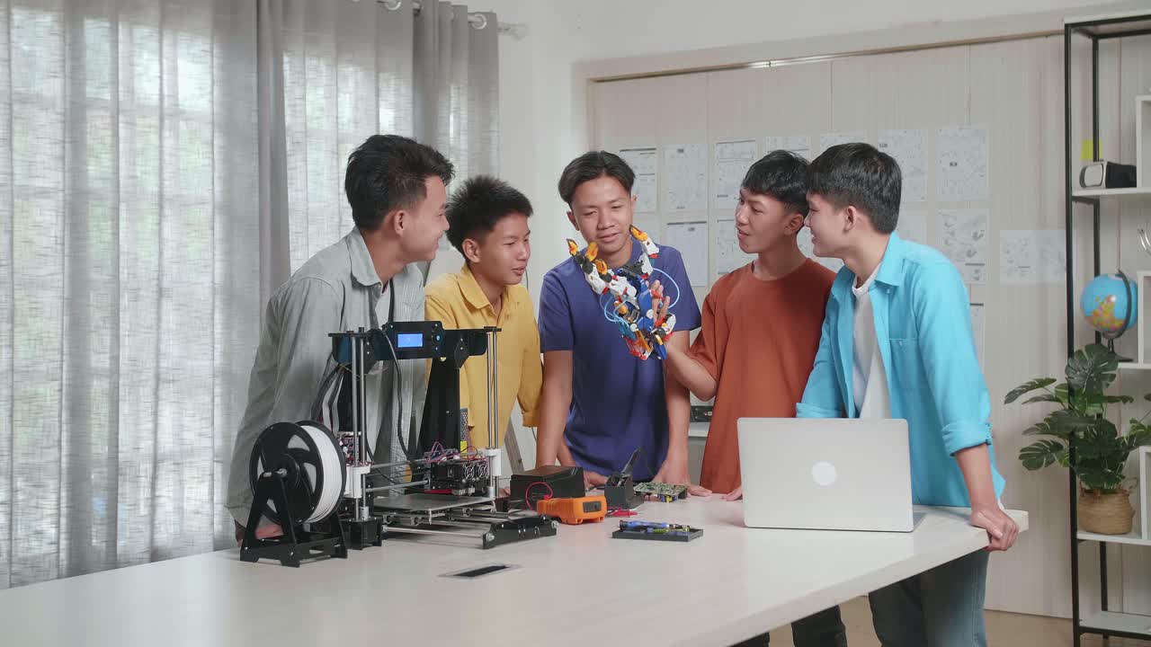 노트북과 3d 프린팅을 가진 젊은 아시아 소년 그룹이 집에서 사이보그 손을 확인하고 있습니다.
