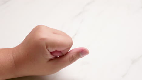 an individual opening and closing her left hand, stretching it a bit, then pinching and massaging herself using her right hand