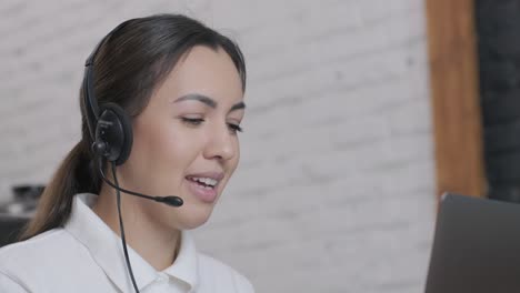 smiling woman call centre operator, customer support agent wears headset consults client online typing on laptop, talk in internet computer chat, helpline operator secretary make conference video call