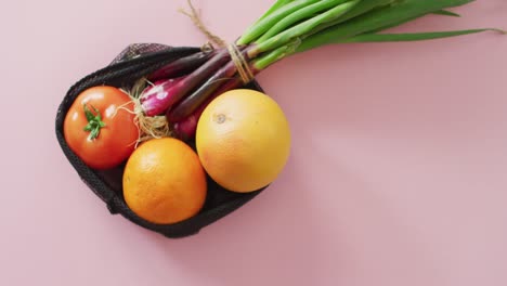 Video-Von-Frischem-Obst-Und-Gemüse-In-Einer-Schwarzen-Tüte-Auf-Rosa-Hintergrund