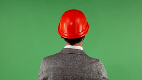 rear view shot of a businessman putting on protective hardhat