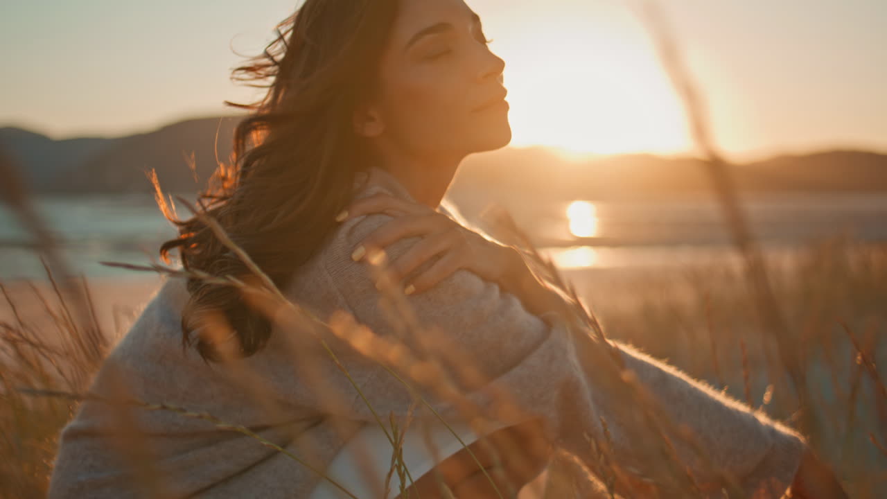 Model posing dry grass field enjoy summer sunset closeup. Happy lady squatting