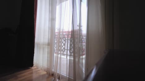 una cortina transparente en la ventana, ligeramente balanceándose en el viento en la habitación.