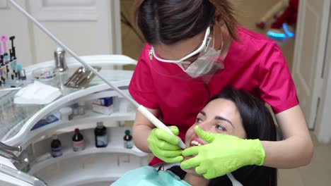 woman at the dental hygienist getting professional tooth whitening and ultrasound cleaning. dentist using saliva ejector or dental pump to evacuate saliva. shot in 4k