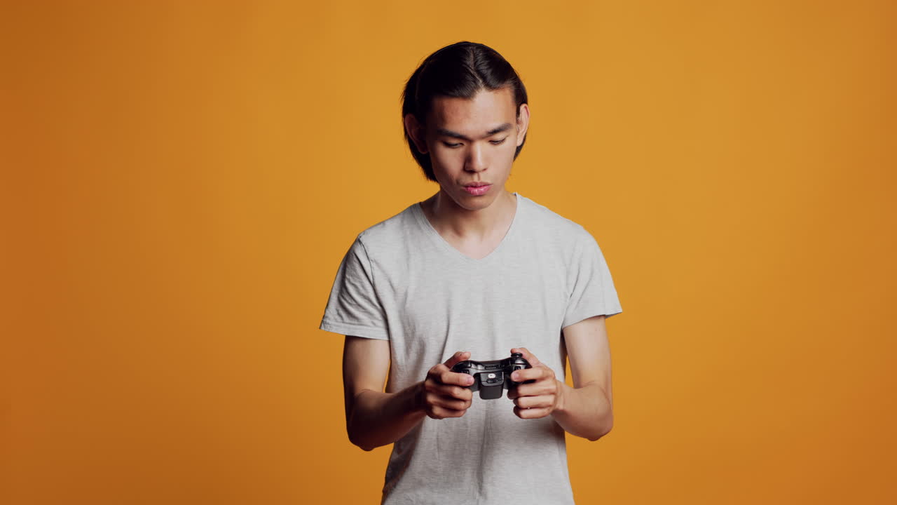 Modern asian man playing videogames on console