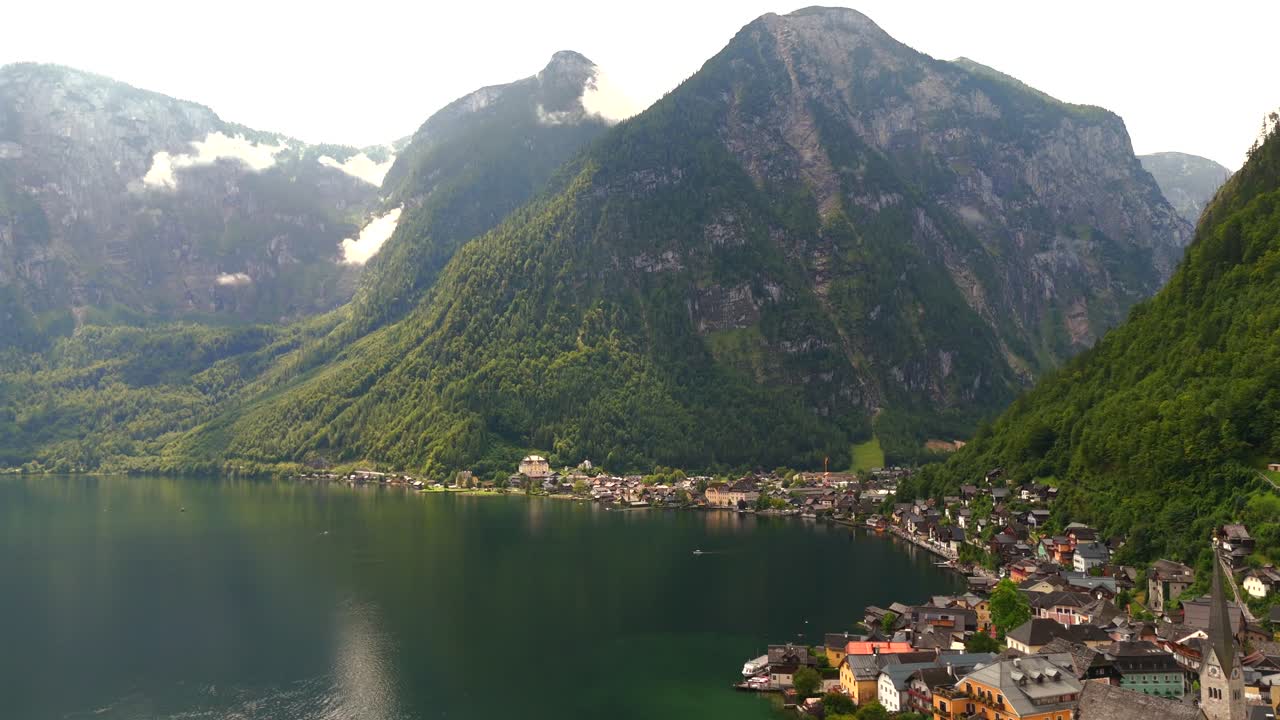 Aerial view of Hallstatt, Austria, captured by drone, showcasing its picturesque lakeside homes, majestic mountains, and the unique charm of this enchanting alpine village.