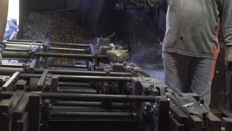 Side-view-of-people-pouring-liquid-metal-into-casts-in-a-factory