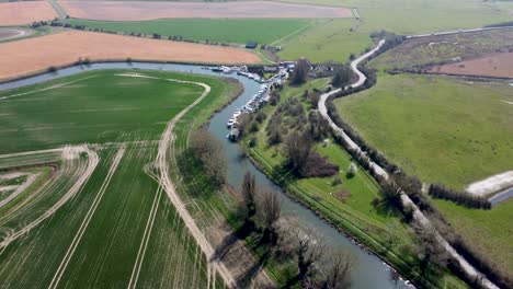 drone flies above the river great stour towards a curve, sun reflects in the water