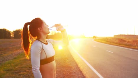 woman drinking water after running