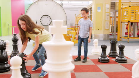 niños de la escuela jugando al ajedrez gigante en un centro de actividades científicas