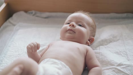 Neugeborener-Junge-Mit-Blondem-Haar-Lächelt-Auf-Dem-Wickeltisch-Liegend