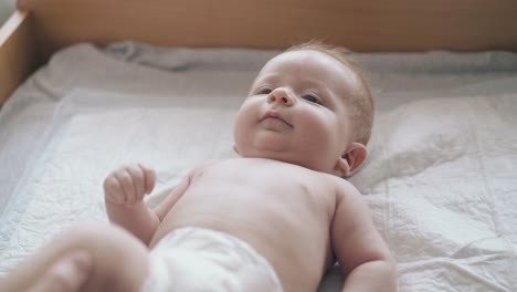 newborn boy with fair hair smiles lying on changing table