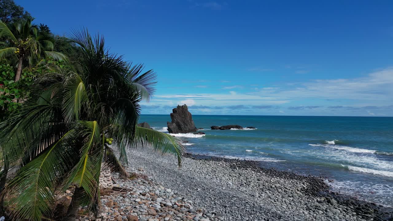 A peaceful shot of the ocean shows calm waters gently lapping against the shore, with a small mountain rising on the side, adding a serene and natural touch to the tranquil scene.