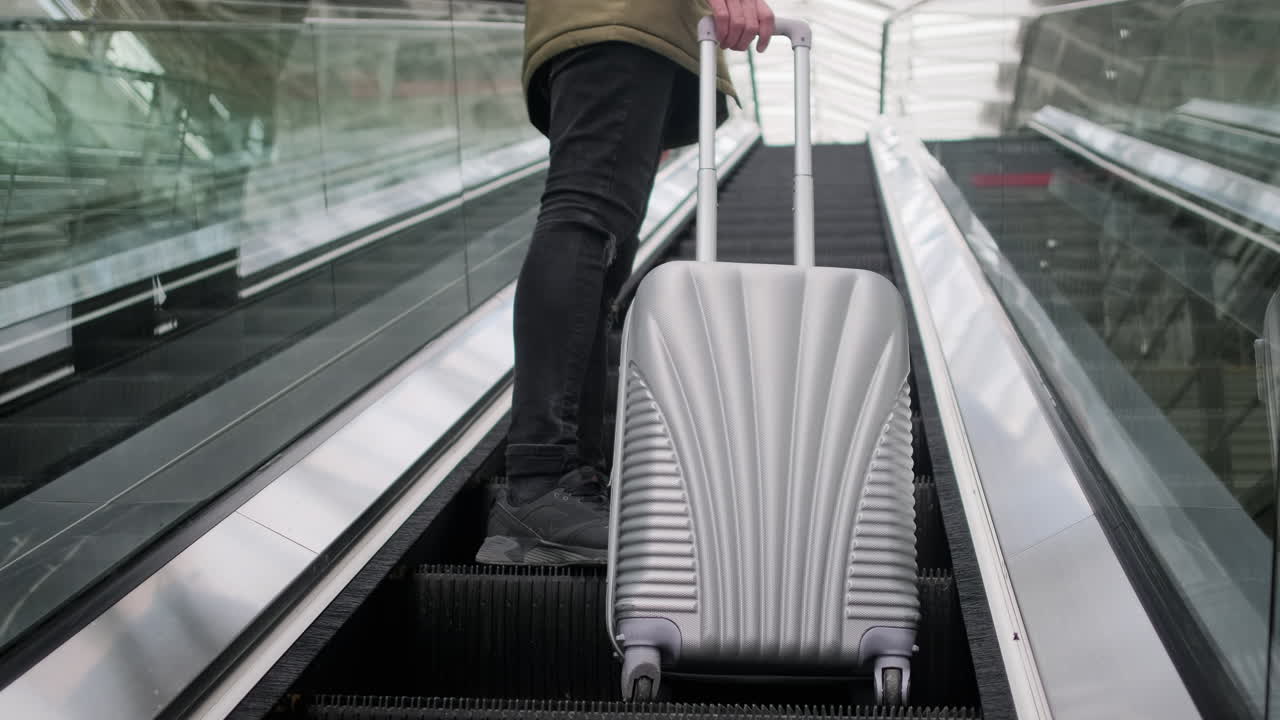 persona subiendo por la escalera mecánica con equipaje
