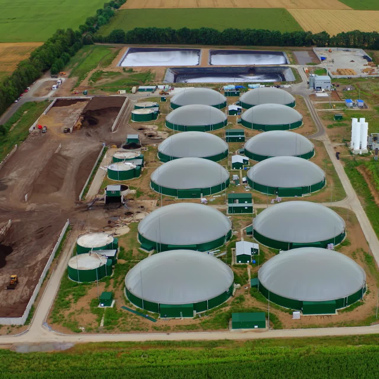Modern biogas plant on green field. Renewable energy from biomass. Agricultural technology for biogas production. Top aerial view.