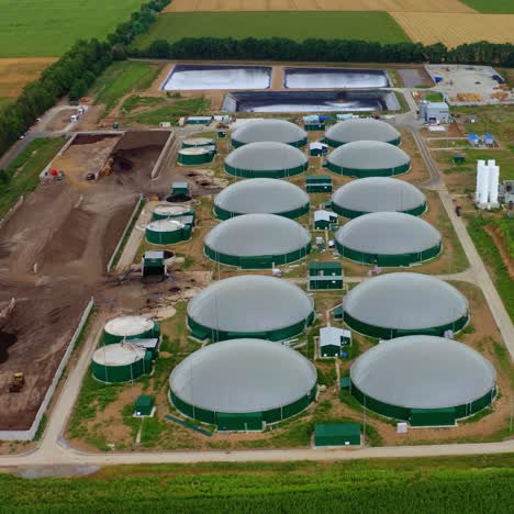 modern biogas plant on green field. renewable energy from biomass. agricultural technology for biogas production. top aerial view.