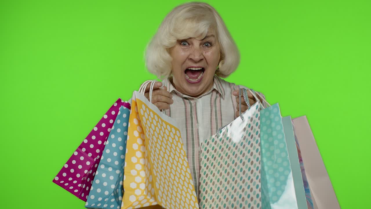 상급 할머니가 쇼핑 가방을 올리고, 축하하고, 구매에 만족하고, 할인합니다.