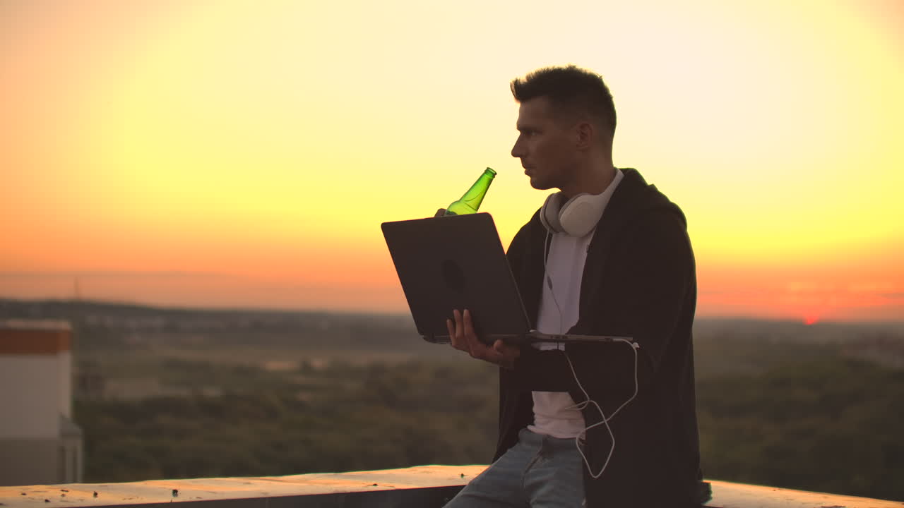 Uomo hipster con un laptop sul bordo del tetto. Freelance al lavoro. Internet mobile wireless. Lavora su Internet.