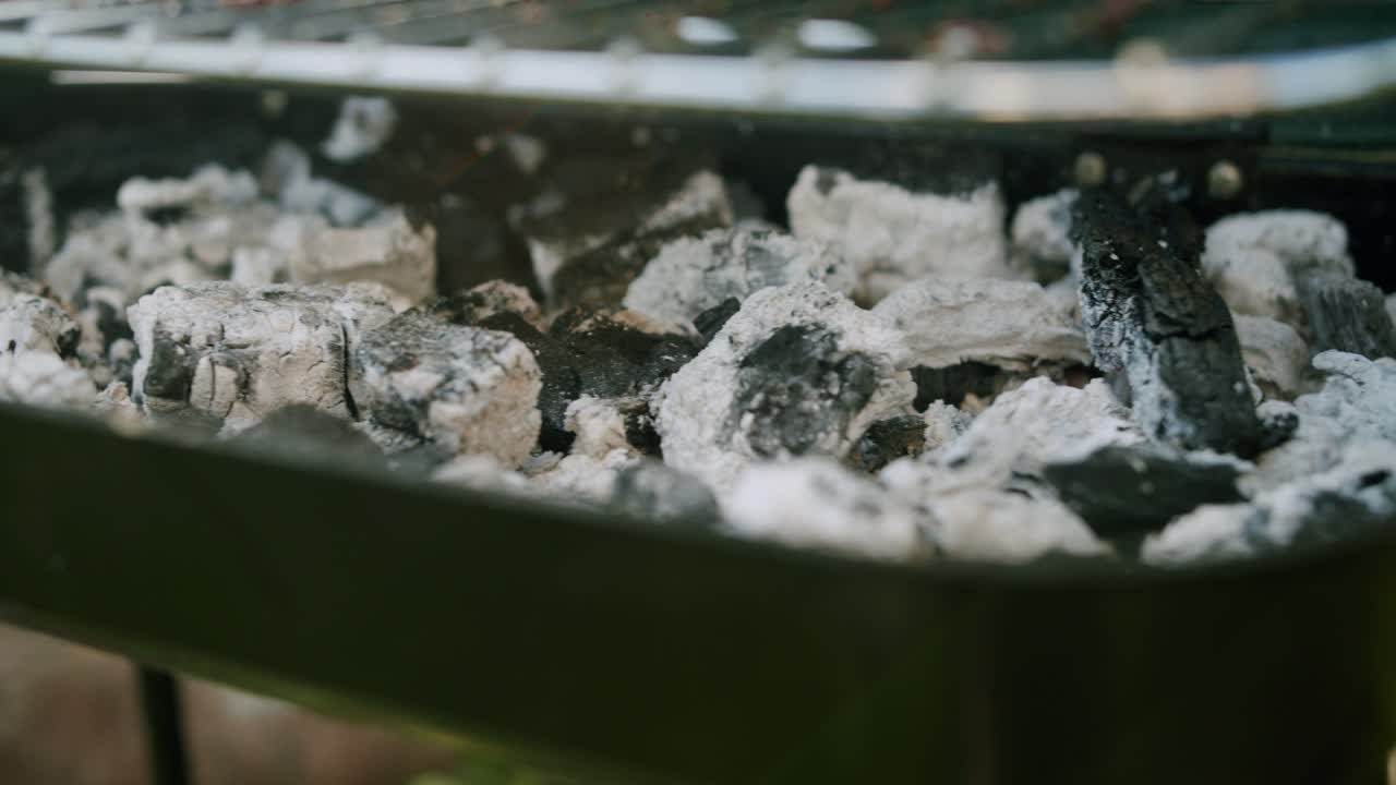 Smoldering Pieces of Coal in a Small Portable Dark Grill in a Garden