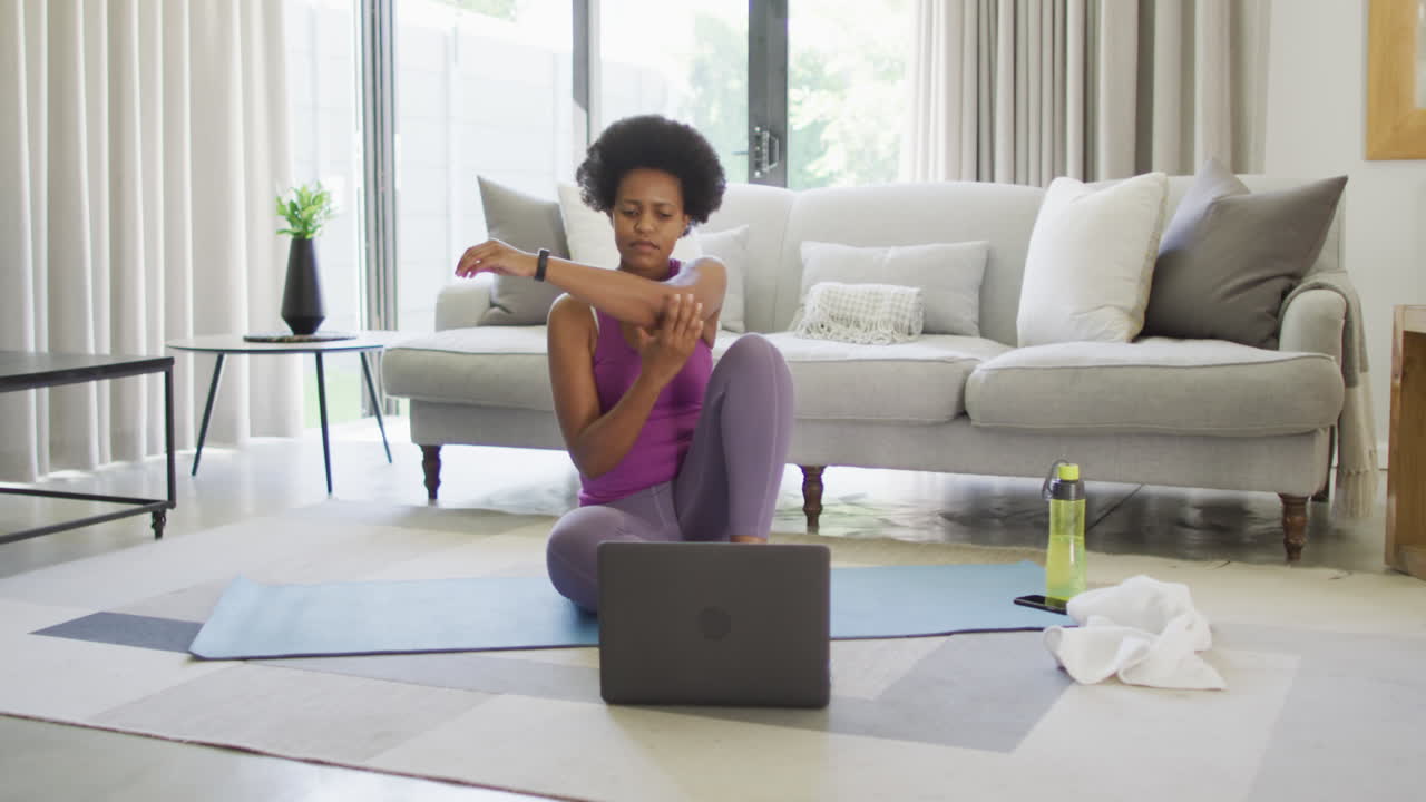 Happy african american wearing sportswear, exercising, using laptop