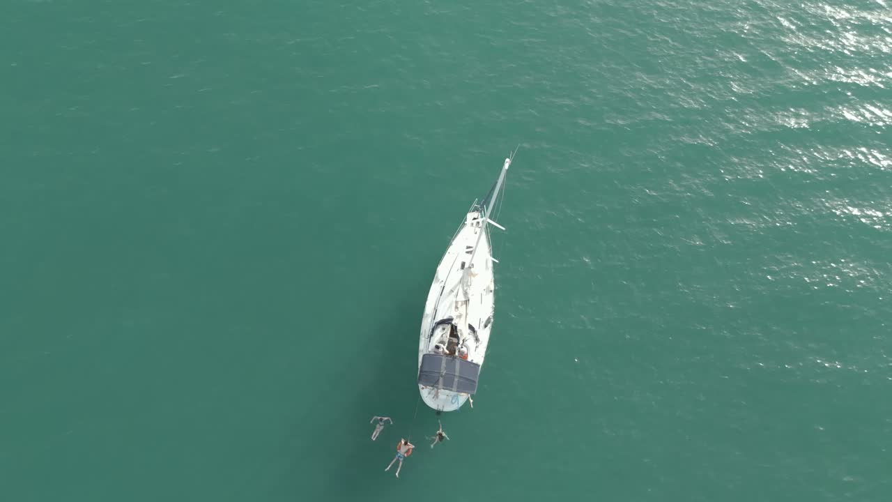 jóvenes nadando y divirtiéndose en el mar junto a su velero