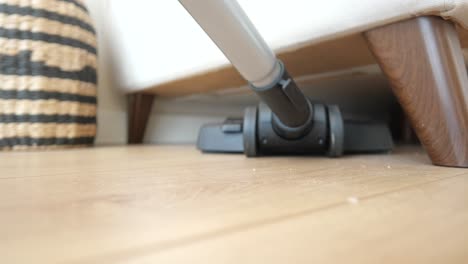 close up of a vacuum cleaner cleaning under a couch