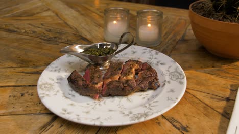 steak is served on a wooden table with candles