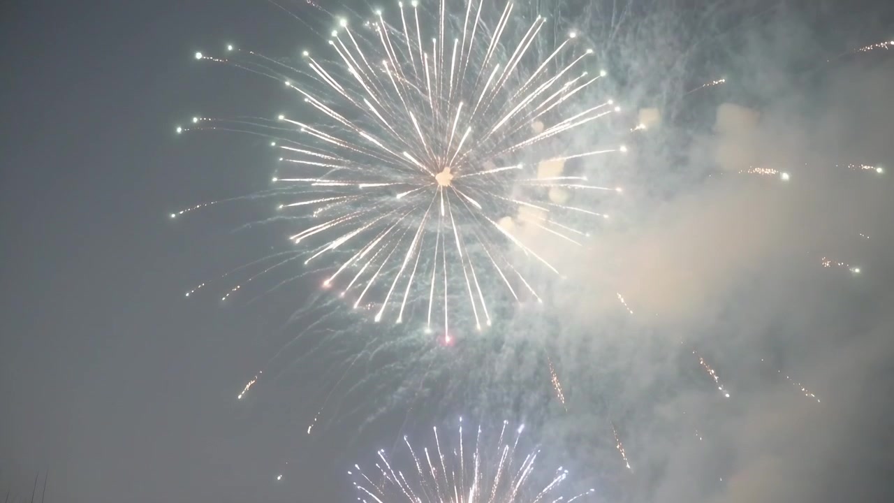 Launching shell large aerial firework spreading trails with minor burst in dusk sky, drifting smoke