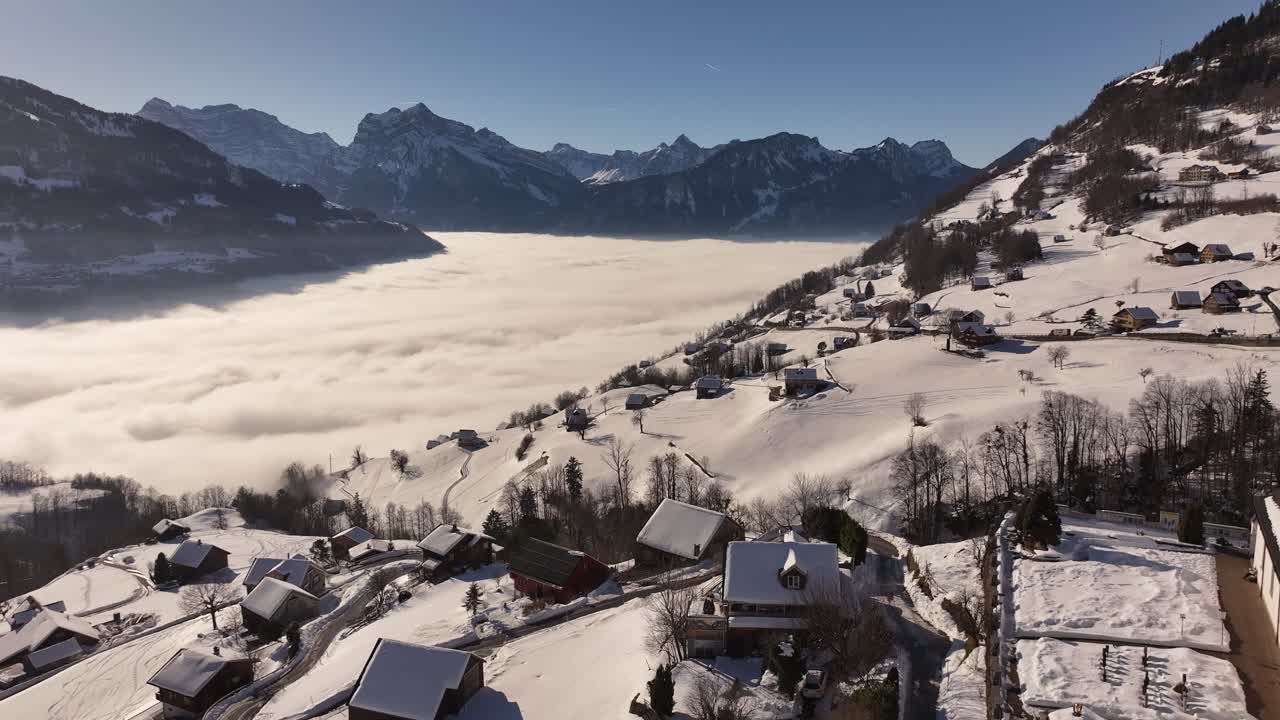 Aerial view of the St. Gallus Church in Amden, Switzerland, perched above a breathtaking sea of fog blanketing the valley.