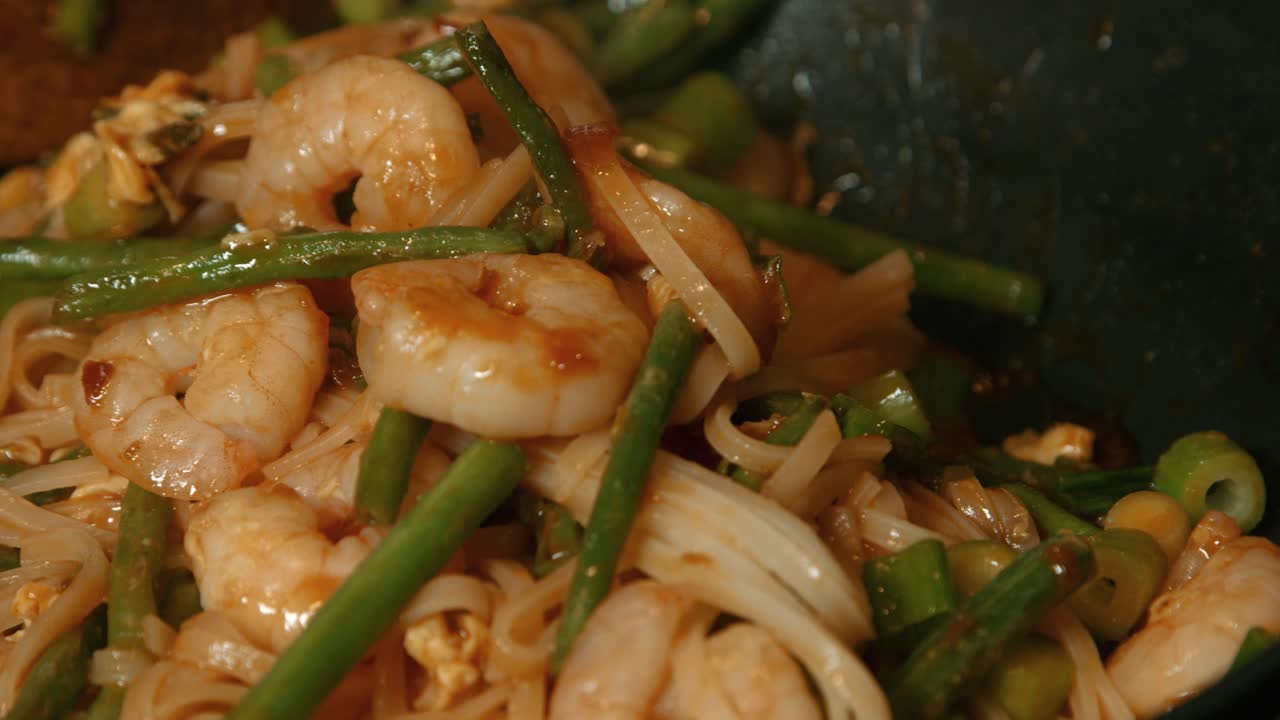 pad thai con camarones rey y fideos cocinando en sartén caliente