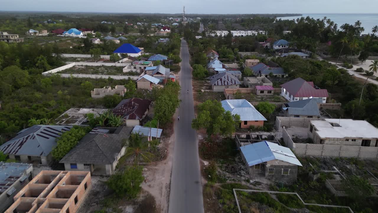 건설 중인 집과 걷는 사람들이 있는 우로아 비치 타운을 가로지르는 주요 도로, 탄자니아 잔지바르, 아프리카, 공중 비행 샷