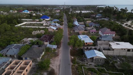 carretera principal a través de la ciudad de playa de uroa con casas en construcción y gente caminando, zanzíbar tanzania, áfrica, tiro aéreo