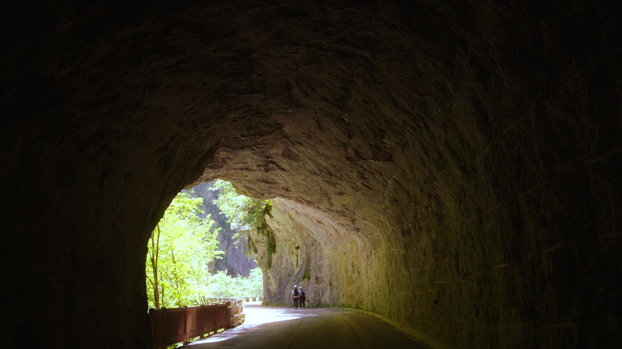 Active tourists wearing helmets explore the unique underground rock passages of Cellina gorge, Italy
