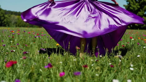 woman in purple satin dress dancing in a flower field