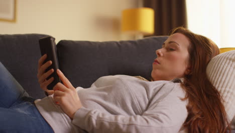 close up of woman lying on sofa at home at streaming or watching movie or show or scrolling internet on mobile phone 5