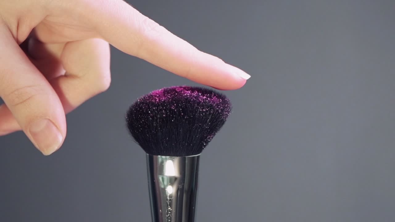 여성 손의 손짓, 손가락이 반이는 화장품 브러쉬에.