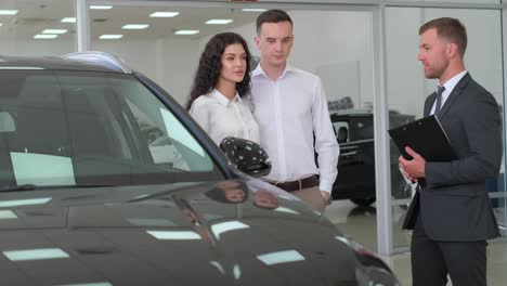 a man and a woman are examining a personal luxury 4k 2025 08 05 00 05 42 utc.mov | automobile, autoshow, beautiful, building