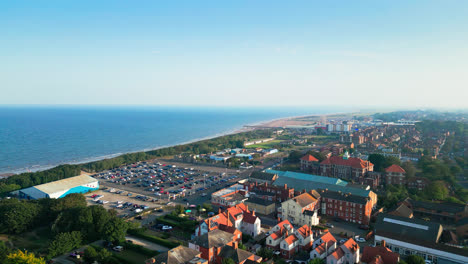 Explore-Skegness,-Lincolnshire's-coastal-treasure,-through-aerial-footage,-featuring-its-expansive-beach,-vibrant-tourist-area,-amusement-park-attractions,-and-famous-pier-during-a-summer-evening