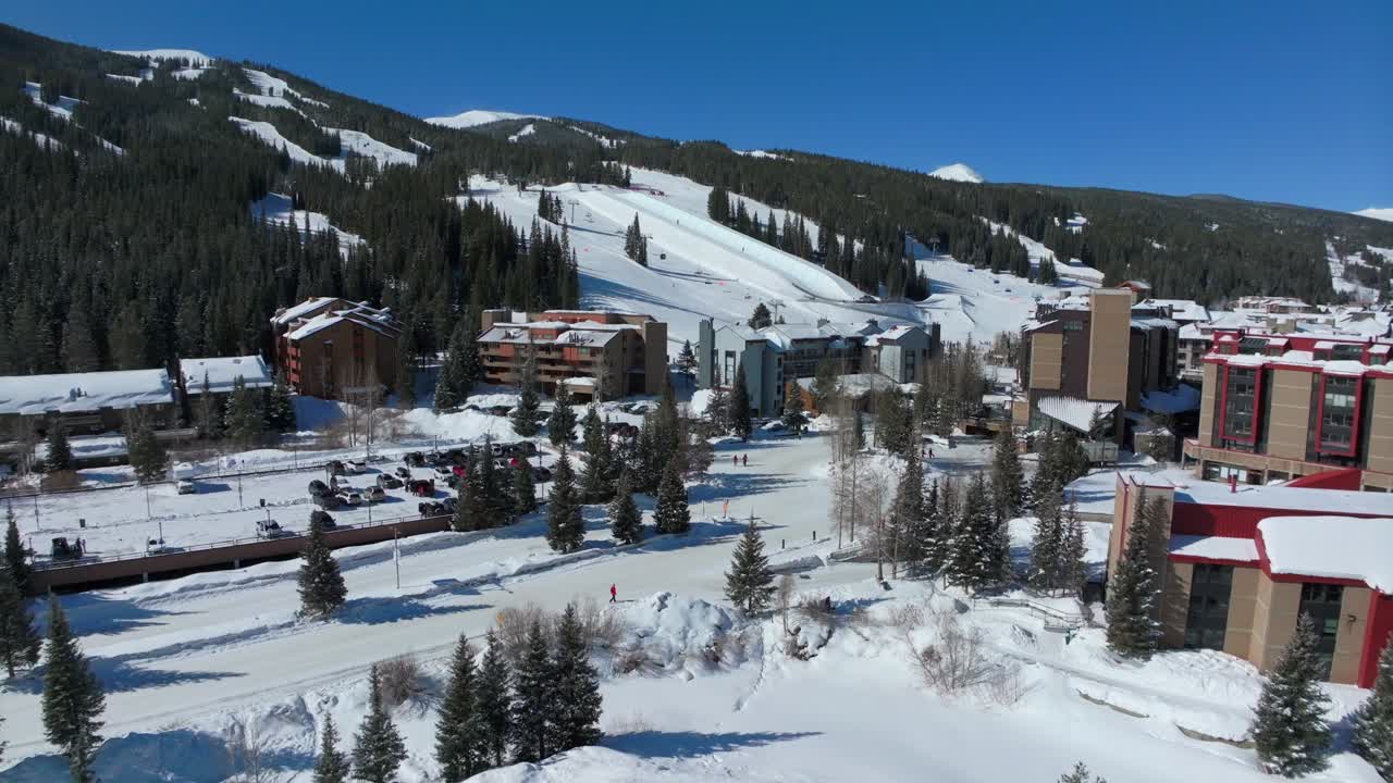 drone aéreo cobre montaña invierno esquí snowboard resort icon pasar estacionamiento alojamiento hoteles colorado temprano en la mañana luz del sol nieve fresca ascensor de esquí multitud cinematográfica hacia adelante pan up movimiento 4k