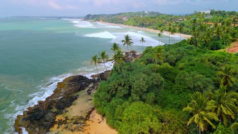 a breathtaking aerial drone shot of sk town surf beach in weligama, sri lanka, where lush jungle meets the ocean.