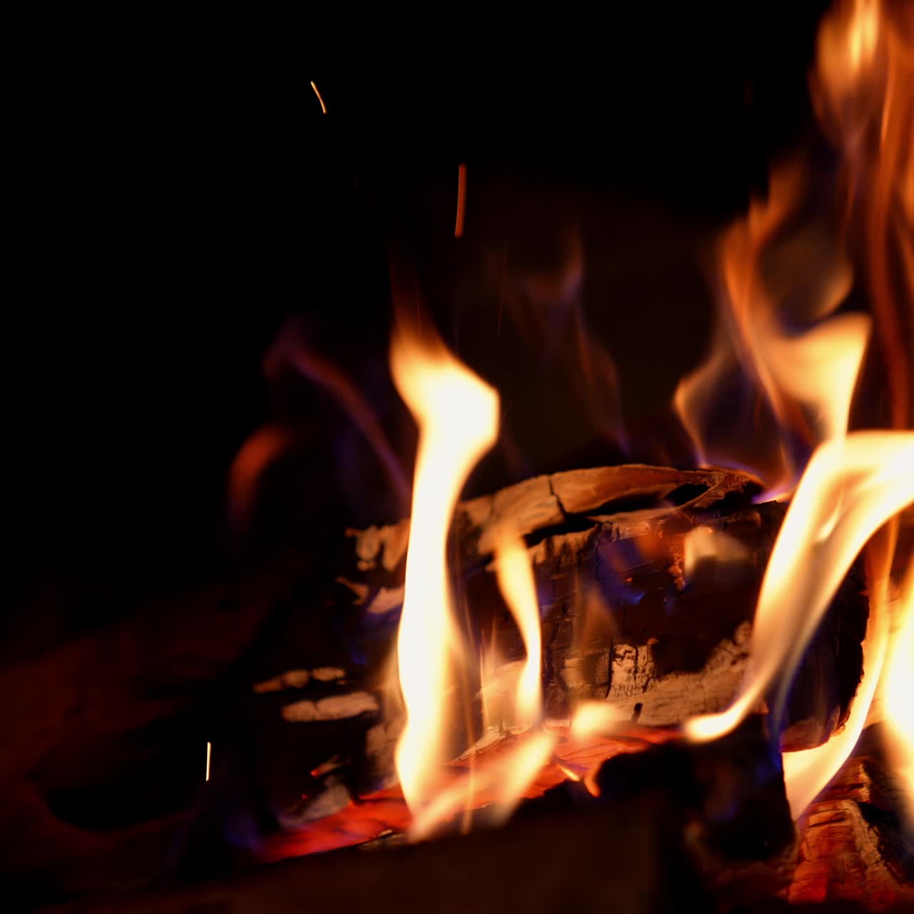 Red and orange tongues of fire on black background. Wood burning in vivid flame in the fireplace. Glowing fire at night. Close-up