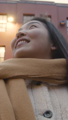 retrato vertical de una joven asiática sonriente que visita el barrio chino en londres, reino unido.