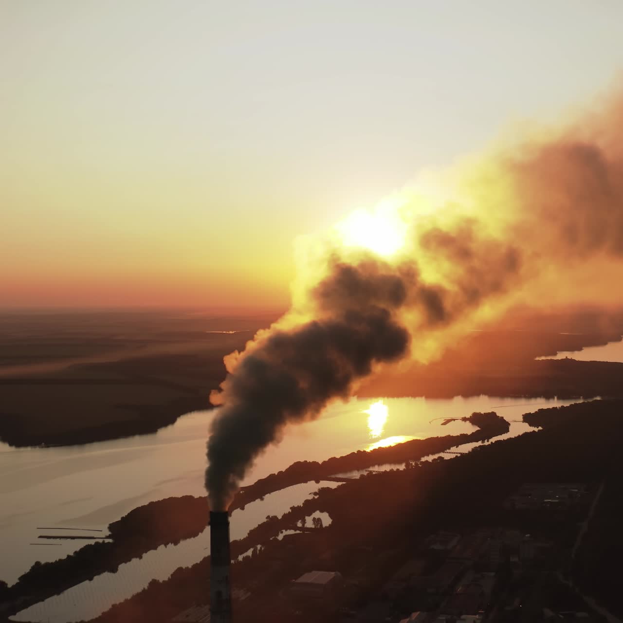 Dirty smoke from industrial chimneys at sunset. Dark chemical fumes released into the atmosphere in the evening. Harmful emissions in the environment. Aerial view