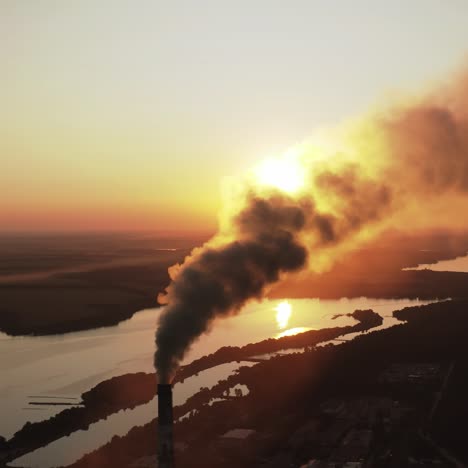 Dirty smoke from industrial chimneys at sunset. Dark chemical fumes released into the atmosphere in the evening. Harmful emissions in the environment. Aerial view
