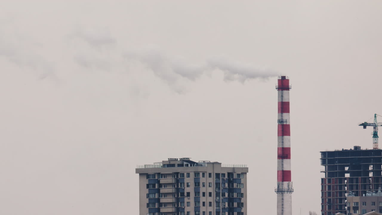 Urban skyline with residential buildings and an industrial chimney emitting smoke