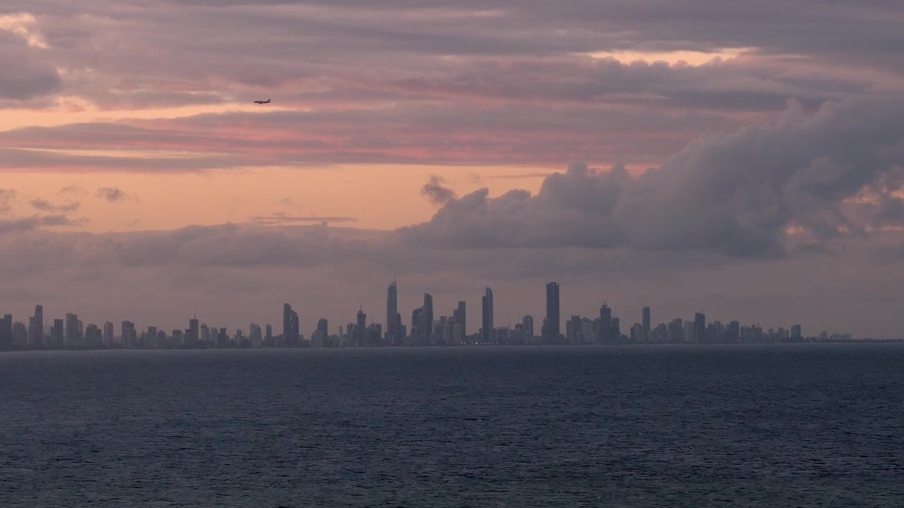 Avión volando sobre los rascacielos de Surfers Paradise al atardecer en Gold Coast, Queensland. Toma panorámica.
