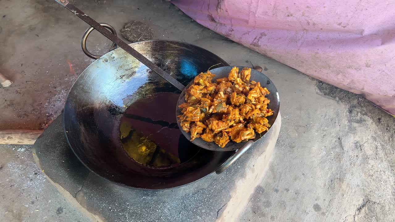 un hombre preparando pakora siendo frito en aceite caliente en el dhaba local en el estilo bihari en la estufa tradicional de tierra en la india